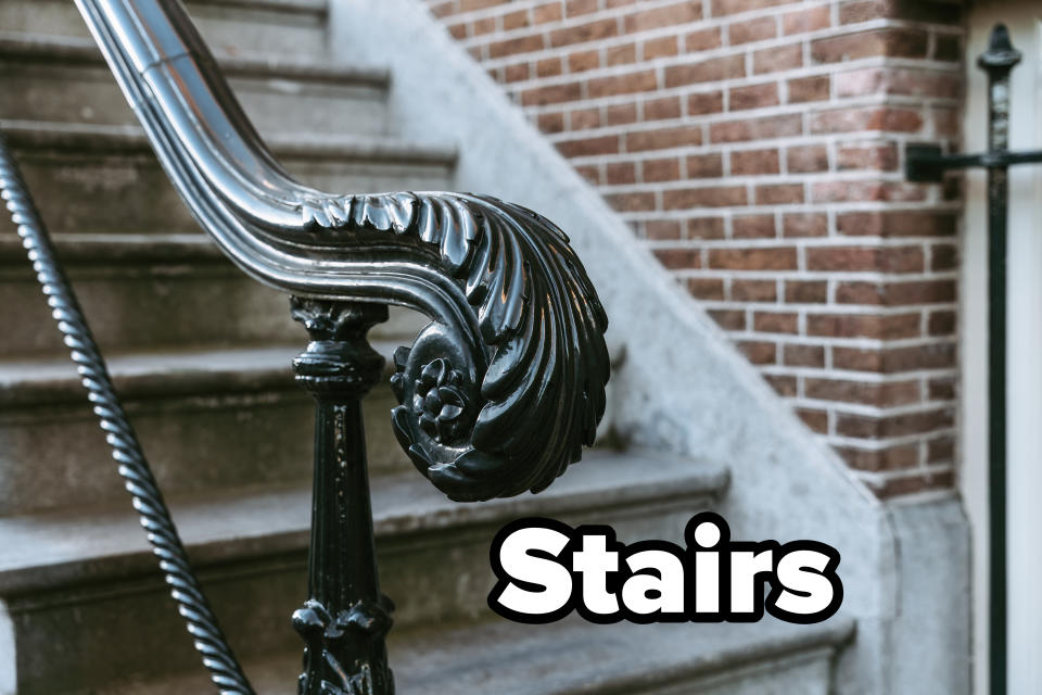 Ornate black iron handrail detail leading up to outdoor stone steps against a brick building