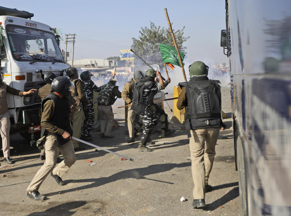 Policemen clash with protesting farmers at the border between Delhi and Haryana state, Friday, Nov. 27, 2020. Thousands of agitating farmers in India faced tear gas and baton charge from police on Friday after they resumed their march to the capital against new farming laws that they fear will give more power to corporations and reduce their earnings. While trying to march towards New Delhi, the farmers, using their tractors, cleared concrete blockades, walls of shipping containers and horizontally parked trucks after police had set them up as barricades and dug trenches on highways to block roads leading to the capital. (AP Photo/Manish Swarup)
