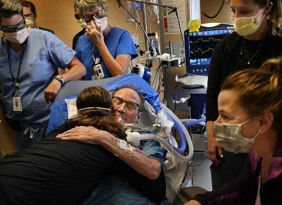 FILE - In this May 3, 2021, file photo, Hennepin County Medical Center patient John Grubb, of St. Michael, hugs and says goodbye to several of his caregivers as his wife, Kelly, lower right, looks on before he is discharged from the hospital in Minneapolis, after spending 81 days on the ECMO heart-lung bypass machine, which has been the treatment of last resort in COVID-19 care. (David Joles/Star Tribune via AP, File)