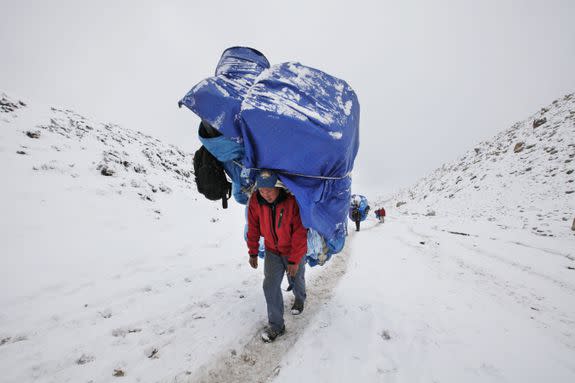 A porter walks with a massive load towards Everest Base Camp near Lobuche, Nepal.