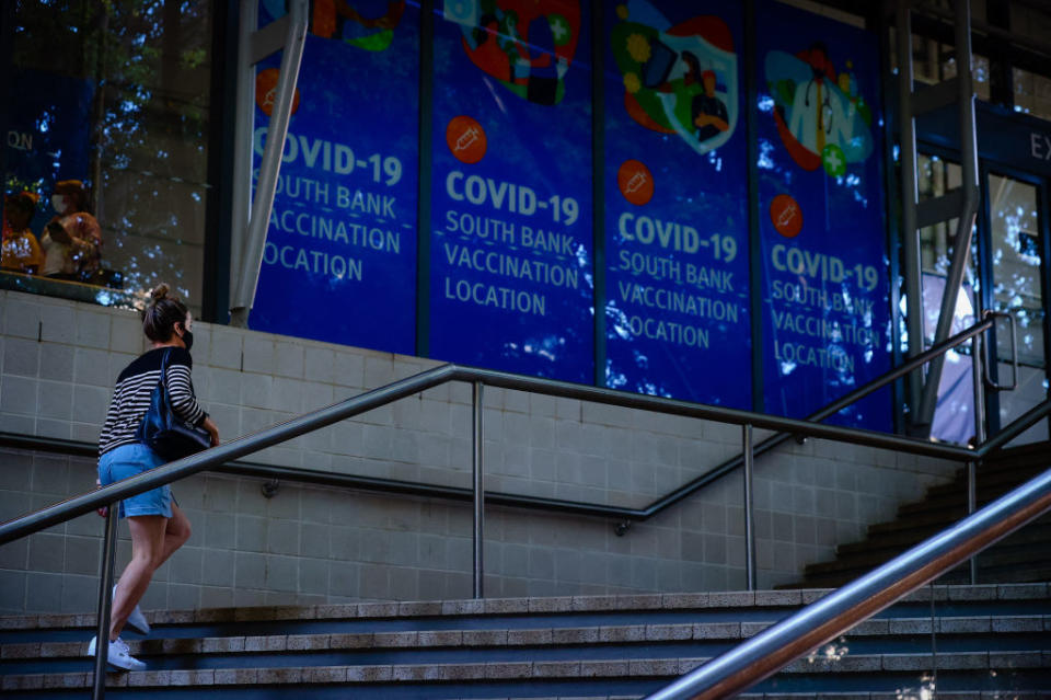 A woman walk past signage at a Covid-19 vaccination hub at the Brisbane Convention and Exhibition Centre in Brisbane.