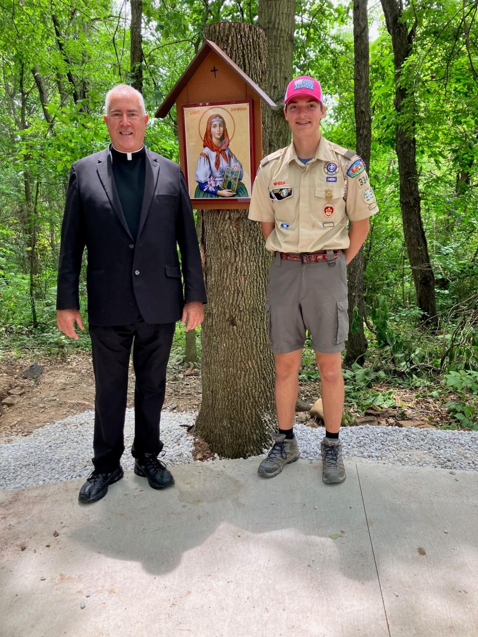 The Rev. David Durkee, pastor of Queen of Heaven Church in Green, and Boy Scout J.P. Moorehead stand at the new shrine to St. Dymphna that Moorehead recently built on the church grounds for his Eagle Scout project.