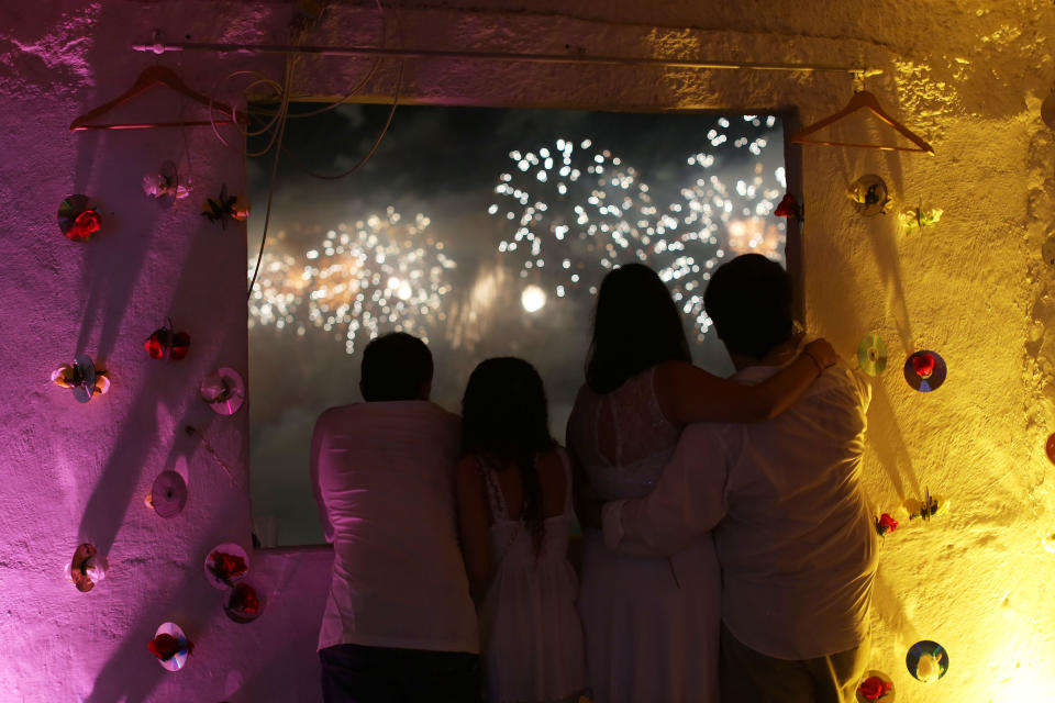 People on a rooftop in the Pavao Pavaozinho slum watch fireworks exploding over Copacabana beach during New Year's Eve celebrations in Rio de Janeiro, Brazil, Wednesday, Jan. 1, 2014. (AP Photo/Leo Correa)