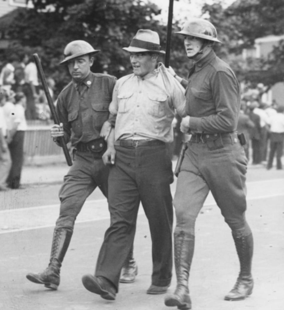 A pair of National Guardsmen take a man they identified as a ringleader in the violence that erupted on Sept. 10, 1934, outside the Sayles Finishing Co. in Lincoln. The Guard was called in after a crowd numbering in the thousands proved too big for local police and mill security to control.