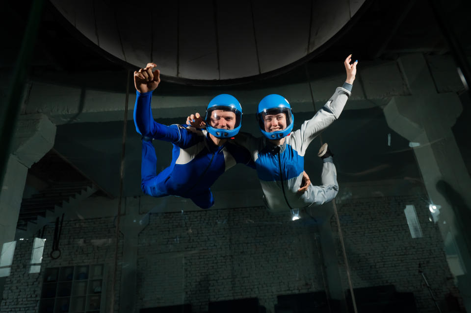 Two people smiling and enjoying indoor skydiving in a wind tunnel