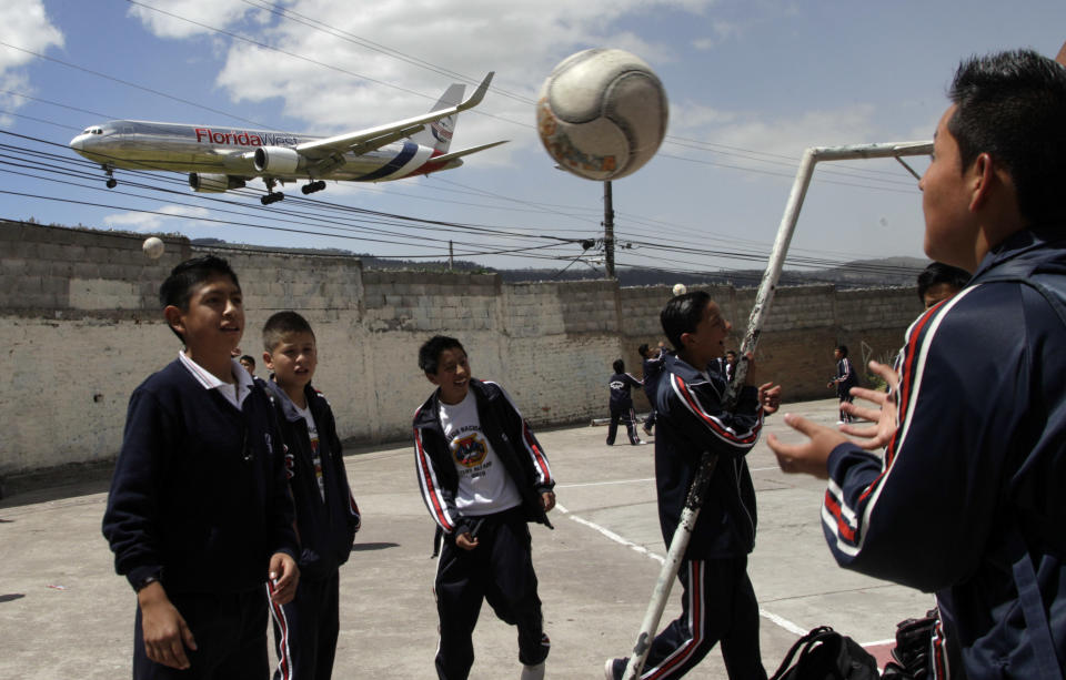 In this Jan. 8, 2013 photo, students play soccer at their school, Eloy Alfaro, as a plane approaches the Mariscal Sucre airport for landing in Quito, Ecuador. Mariscal Sucre airport sat amid cornfields when it was christened in 1960. On Feb. 19, the airport will close and a new airport will be built in an agricultural setting 12 miles (20 kilometers) northeast of the city. While the old airport can be reached from downtown in 20 minutes or so it will take at least an hour to get to the new airport, and no train-to-the-plane is yet planned. (AP Photo/Dolores Ochoa)