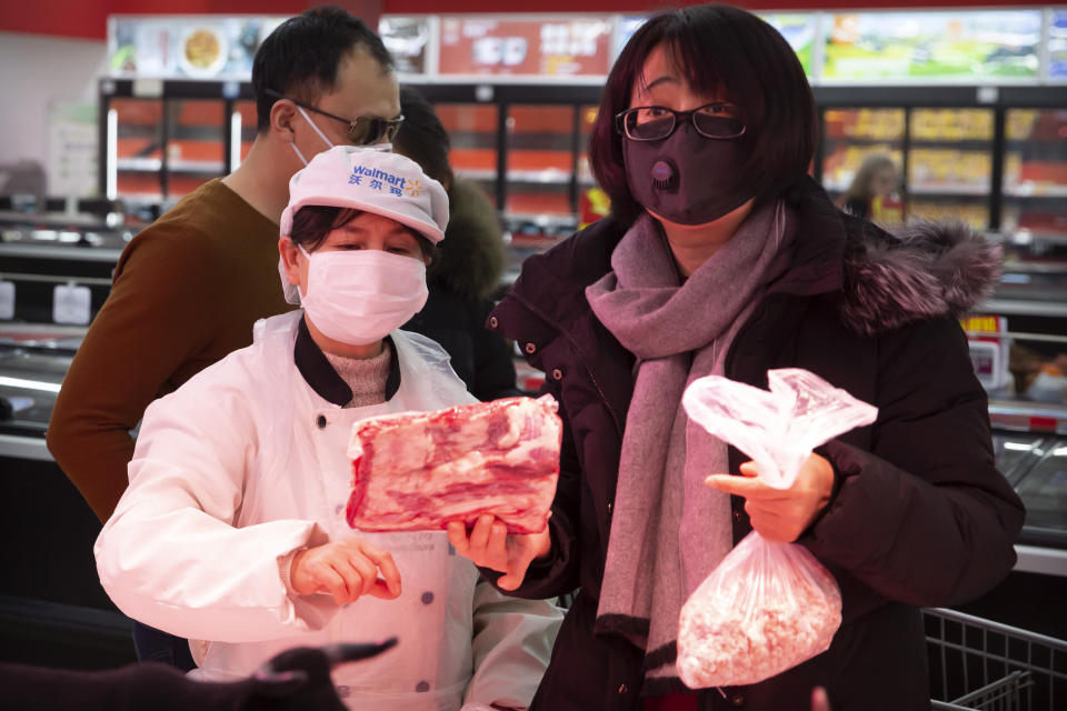 People wear face masks as they shop for groceries at a supermarket in Beijing, Tuesday, Jan. 28, 2020. China's death toll from a new viral disease that is causing mounting global concern rose by 25 to at least 106 on Tuesday as the United States and other governments prepared to fly their citizens out of the locked-down city at center of the outbreak. (AP Photo/Mark Schiefelbein)