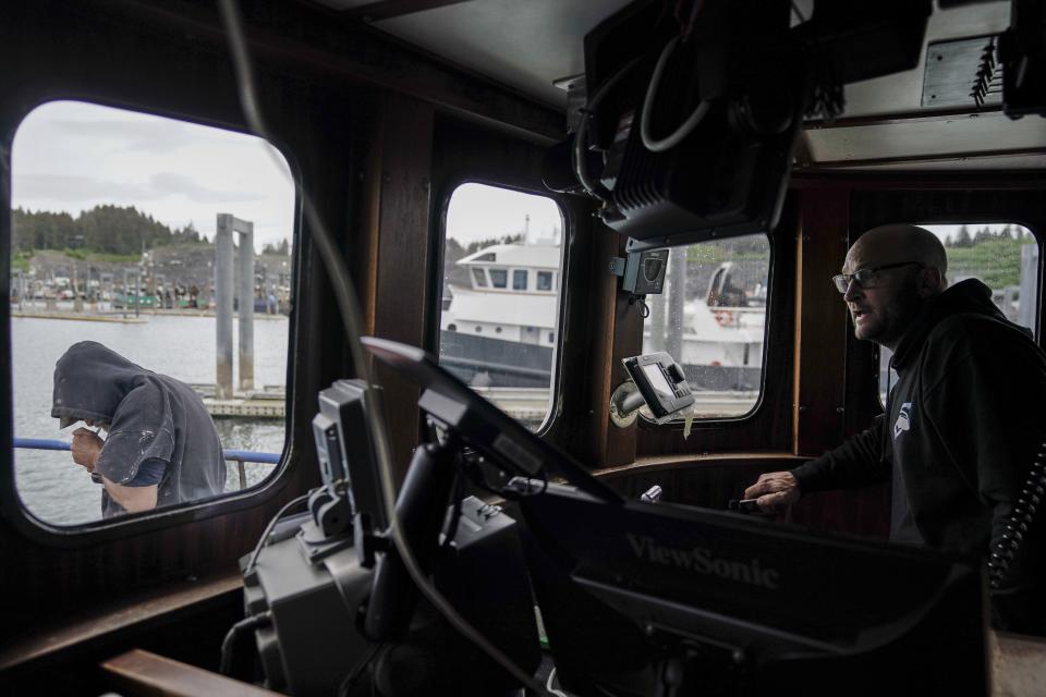 Kevin Abena, right, who runs a fishing business with his father, looks out as he prepares to dock in Saint Herman Harbor after unloading salmon at a processor, Sunday, June 25, 2023, in Kodiak, Alaska. They rely on tendering to stay afloat in the wake of the crab fishery closure. His vessel Big Blue, stopped fishing for most crab in Bristol Bay in 2010, but they still own access rights and take a percentage from other boats that fish their quota. (AP Photo/Joshua A. Bickel)