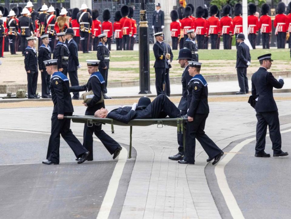 A Police officer is carried off on a stretcher after collapsing while standing guard at Westminster Abbey, London ahead of the State Funeral of Queen Elizabeth II. (Photo by Rowan GRIFFITHS / POOL / AFP) (Photo by ROWAN GRIFFITHS/POOL/AFP via Getty Images)