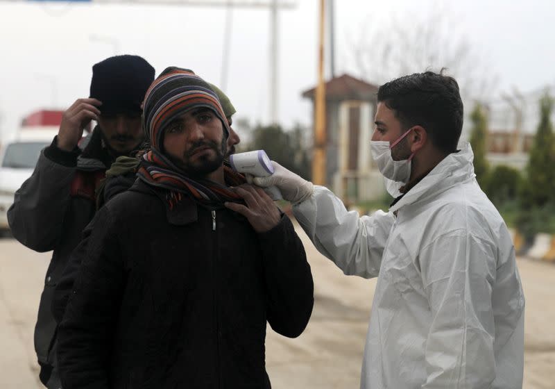 Health worker tests a man as part of security measures to avoid coronavirus, at the Bab el-Salam border crossing between the Syrian town of Azaz and the Turkish town of Kilis