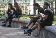 People eat lunch in a park in London, Monday, Sept. 21, 2020. Britain's top medical advisers have painted a grim picture of exponential growth in illness and death if nothing is done to control the second wave of coronavirus infections, laying the groundwork for the government to announce new restrictions later this week.(AP Photo/Frank Augstein)