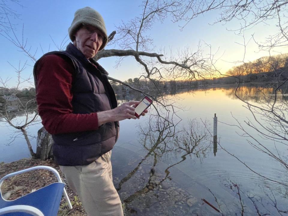 Steve Waller, of Centerville, demonstrates how he uses his iPhone to collect water temperature data read by a digital thermometer at the herring run next his property on Long Pond.