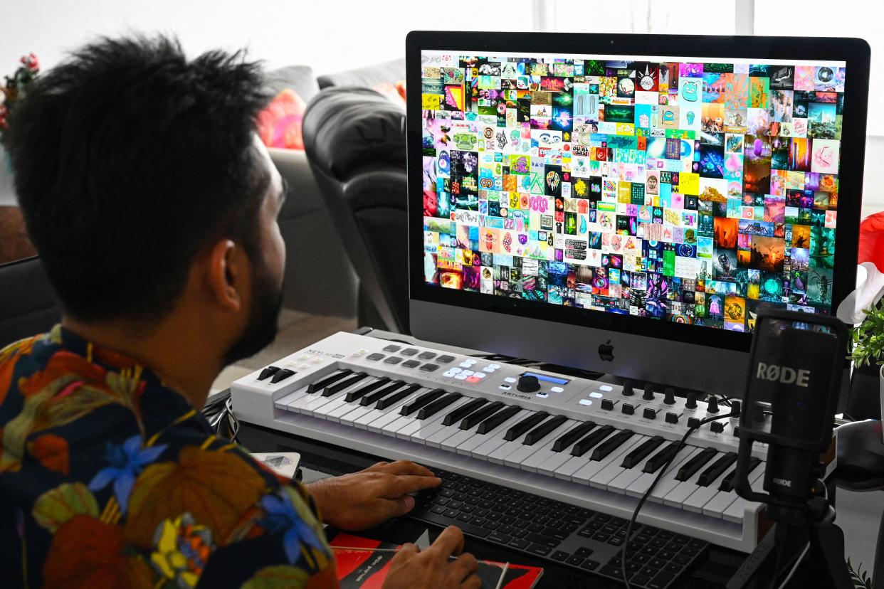 <p>Picture taken on April 7, 2021 shows blockchain entrepreneur Vignesh Sundaresan, also known by his pseudonym MetaKovan, showing the digital artwork non-fungible token (NFT) ‘Everydays: The First 5,000 Days” by artist Beeple</p> (AFP via Getty Images)