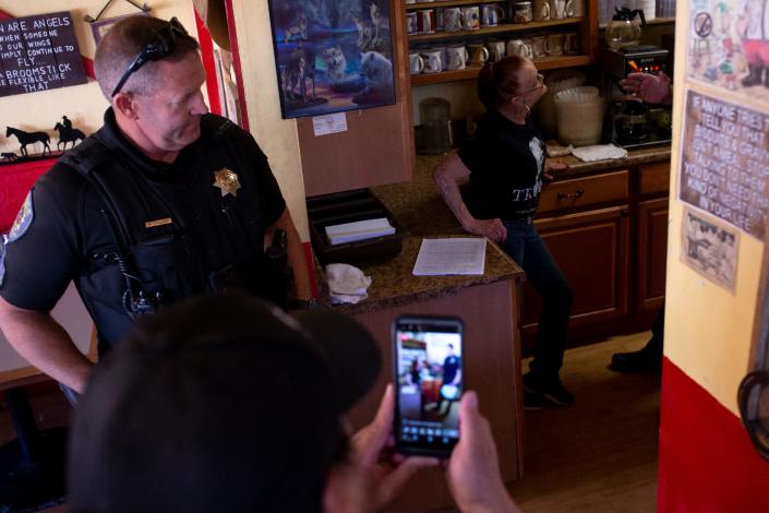 Nohl Rosen filme alors que des policiers de Wickenburg informent Debra Thompson qu'elle doit fermer son restaurant et se conformer à l'ordre de l'État du gouverneur Doug Ducey le 1er mai 2020 au Horseshoe Cafe à Wickenburg, en Arizona.