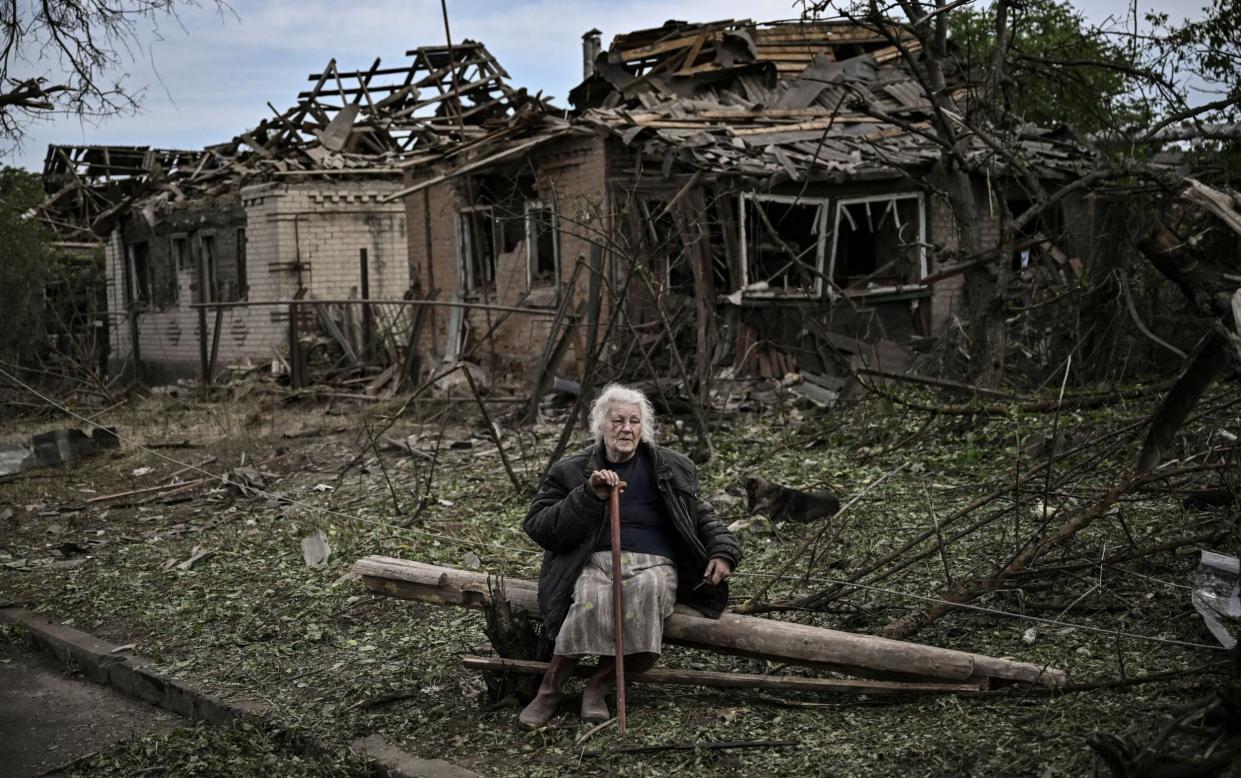 A woman sits in front of houses destroyed by Russian missiles, which killed an elderly woman, in the city of Druzhkivka in the eastern Ukrainian region of Donbas - ARIS MESSINIS/AFP