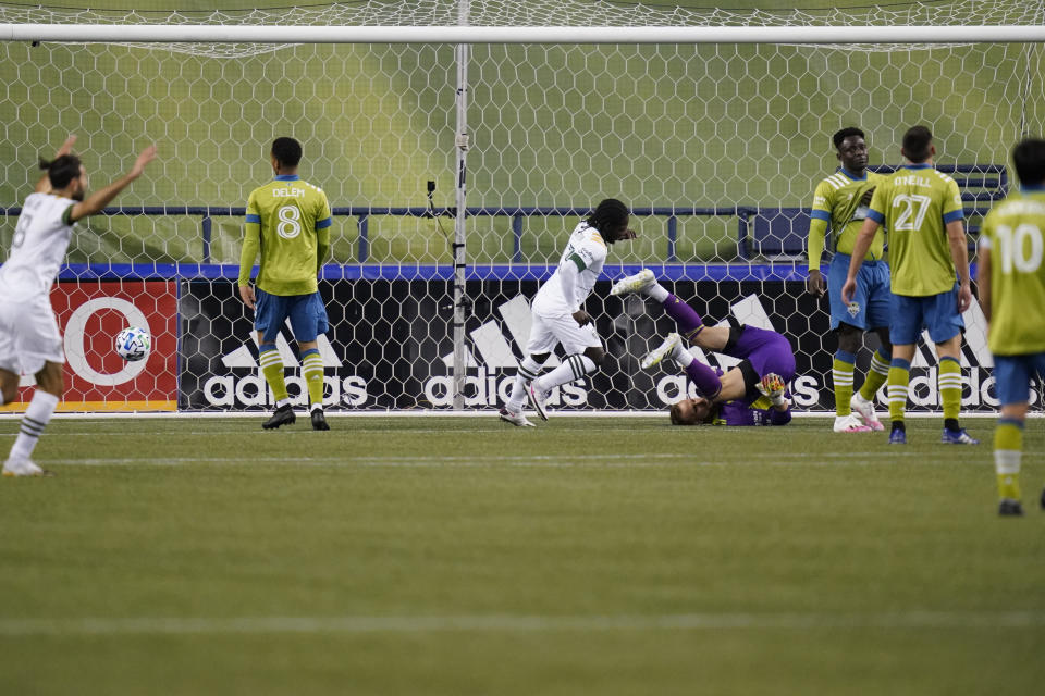 Seattle Sounders goalie Stefan Frei, right, tumbles to the turf as the Portland Timbers score in the first half of an MLS soccer match Thursday, Oct. 22, 2020, in Seattle. (AP Photo/Elaine Thompson)