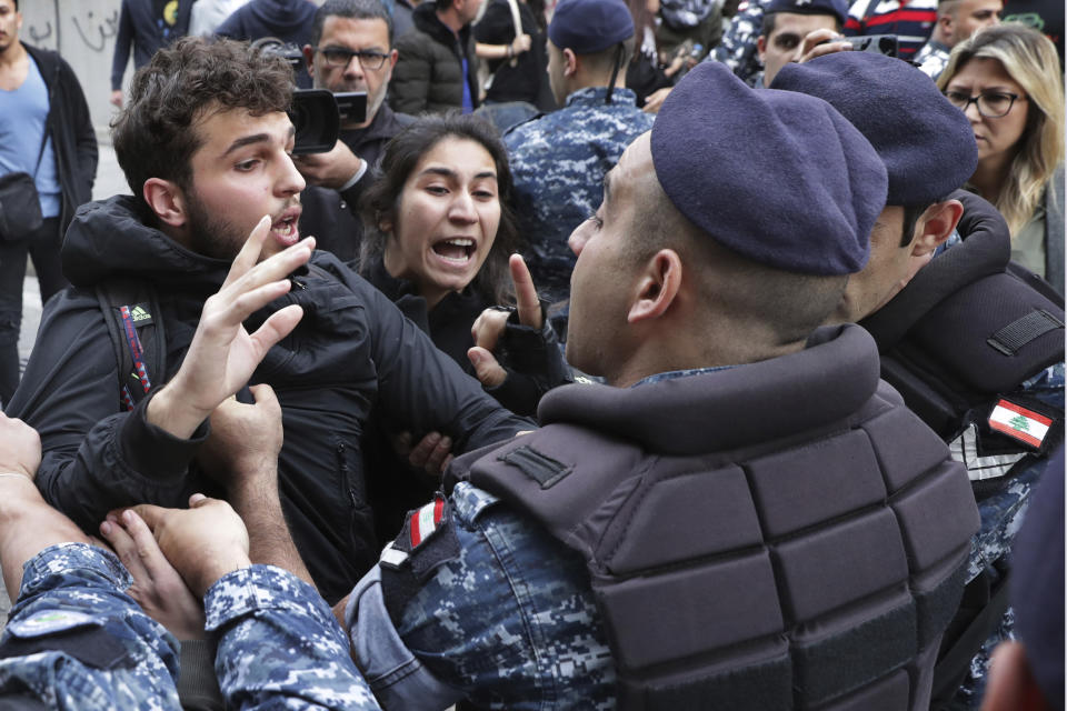 Riot police scuffle with anti-government protesters blocking a road in Beirut, Lebanon, Monday, Nov. 25, 2019. A key road has reopened in the Lebanese capital following clashes throughout the night between rival groups. The confrontations began when protesters blocked the street and were attacked by supporters of the two main Shiite political parties, Hezbollah and Amal. (AP Photo/Hassan Ammar)