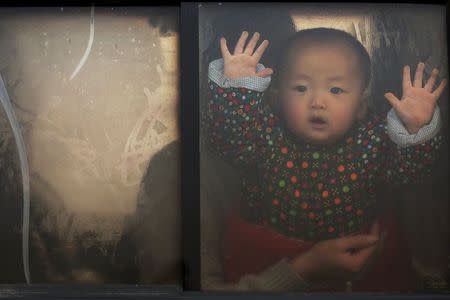 A baby looks through the window of a vehicle stranded on a highway between Beijing and Hebei province, China, that is closed due to smog on an extremely polluted day November 30, 2015. REUTERS/Damir Sagolj