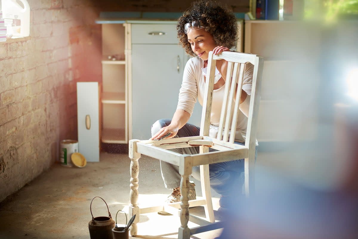 A woman refurbishes an old chair.