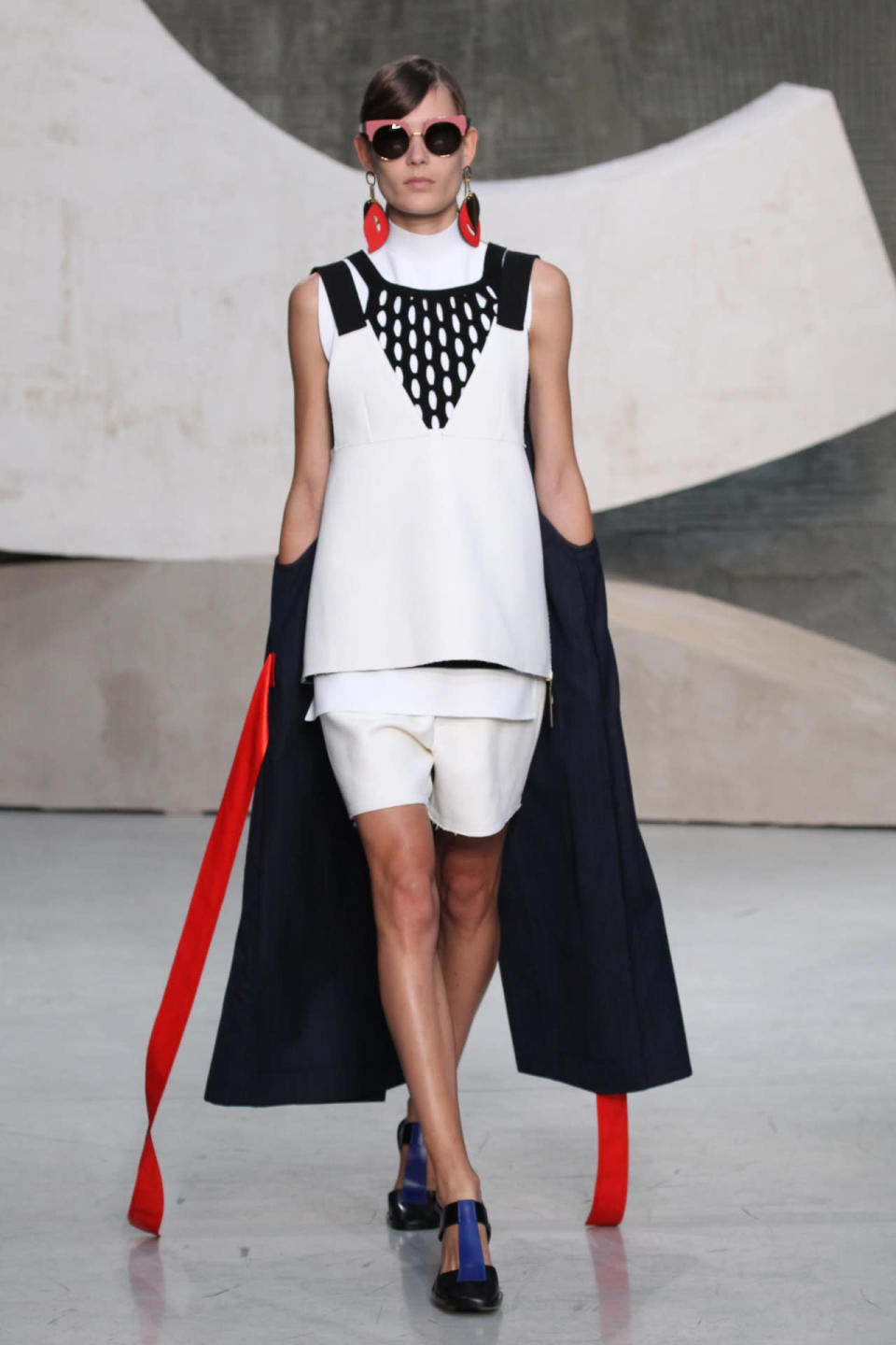 A model wears a black coat and white apron top at Marni’s spring 2016 show in Milan. (Photo: Getty Images.)