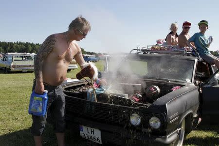 A Norwegian car owner tries to cool down the overheated engine of a 1963 Chevrolet Impala at the Power Big Meet show in Vasteras, Sweden, July 2, 2015. REUTERS/Philip O'Connor