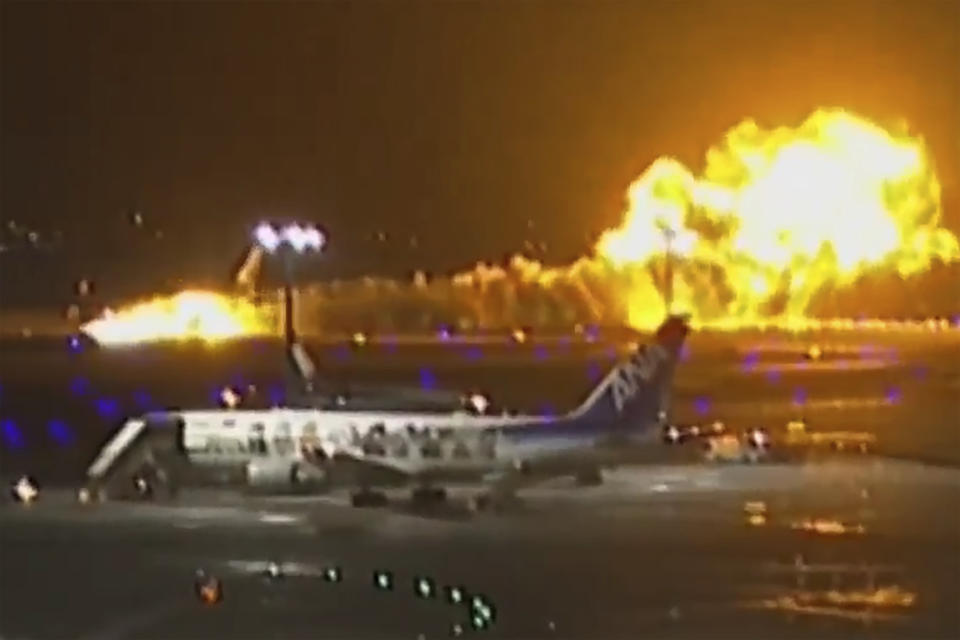 FILE - In this image made from video, a Japan Airlines plane, in the back, is seen on fire on the runway of Haneda airport in Tokyo, on Jan. 2, 2024. The 379 passengers of Japan Airlines Flight JAL-516 didn't expect their plane to burst into flames just as it was about to touchdown at Tokyo’s Haneda airport Tuesday evening. A smaller coast guard Bombardier Dash-8 aircraft, preparing to take off to deliver urgent aid to quake-hit central Japan, was using the same runway when the two collided. The Associated Press collected accounts from witnesses, officials and transcripts of the traffic controls communication. (NTV via AP, File)