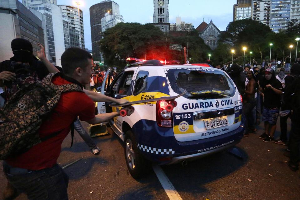 Demonstrators attack a municipal police car to protest the upcoming World Cup and demand better public services in Sao Paulo, Brazil, Saturday, Jan. 25, 2014. Last year, millions of people took to the streets across Brazil complaining of higher bus fares, poor public services and corruption while the country spends billions on the World Cup, which is scheduled to start in June. (AP Photo/Nelson Antoine)