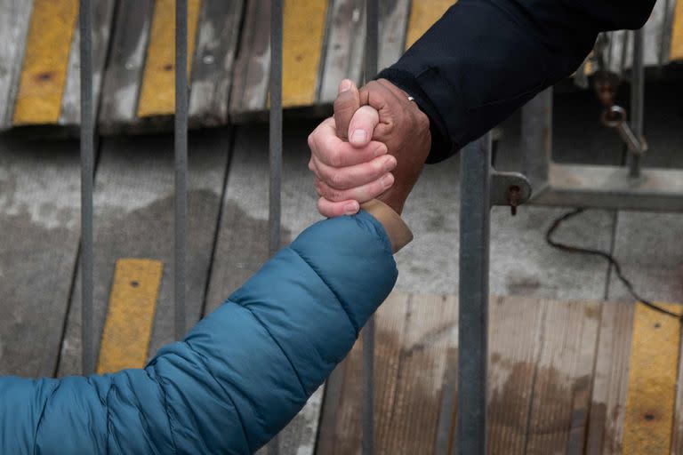 Un miembro de la Fuerza Fronteriza del Reino Unido ayuda a un migrante a desembarcar a su llegada a la Marina en Dover, sureste de Inglaterra, el 24 de noviembre de 2021.