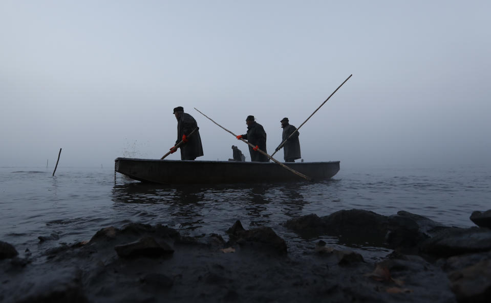 In this picture taken on Thursday, Nov. 15, 2018, fishermen on a small boat take part in the traditional fish haul of the Krcin pond near the village of Mazelov, Czech Republic. Czechs will have to pay more for their traditional Christmas delicacy this year after a serious drought devastated the carp population this year. (AP Photo/Petr David Josek)