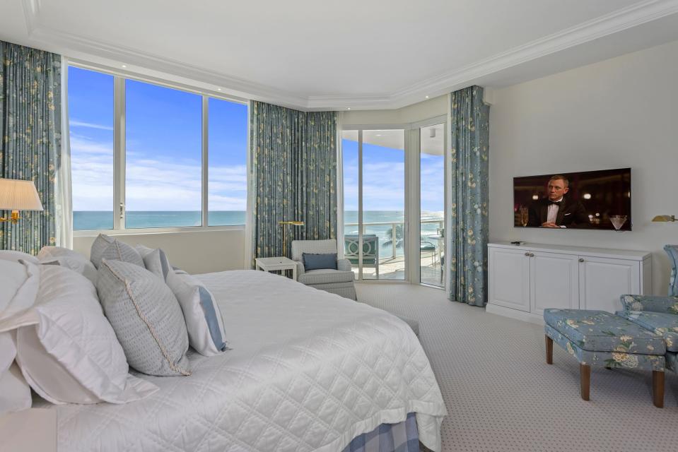 Windows in the primary bedroom capture sea views, with glass doors opening onto the oceanside balcony.