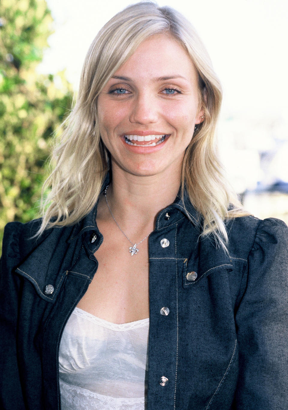 Cameron Diaz smiling at an outdoor event, wearing a denim jacket over a lace top