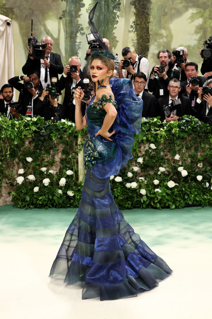 Zendaya in an elaborate gown with ruffles poses in front of photographers