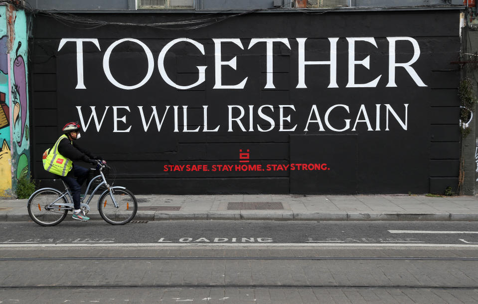 A man wearing a protective face mask cycles past a mural in Dublin as the UK and Ireland continues in lockdown to help curb the spread of the coronavirus.