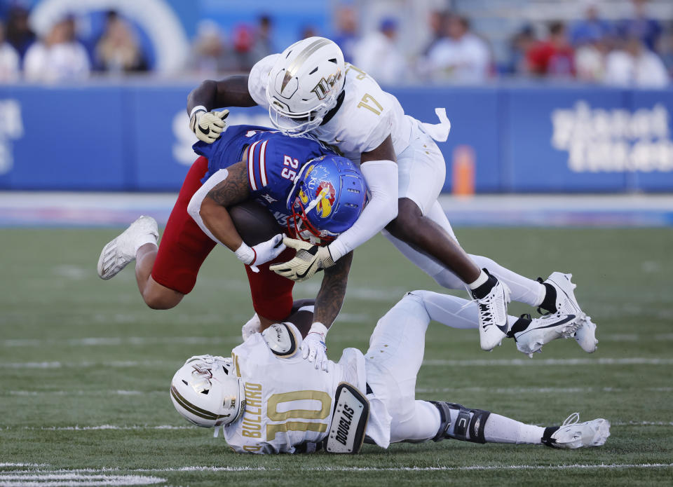 Kansas running back Dylan McDuffie (25) is tackled by Central Florida linebacker Rian Davis (17) and defensive back Quadric Bullard (10) after a 9-yard run for a first down during the second half of an NCAA college football game Saturday, Oct. 7, 2023, in Lawrence, Kan. (AP Photo/Colin E. Braley)