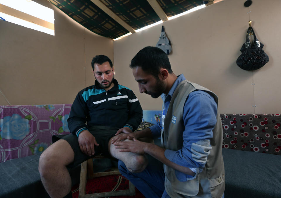 In this Thursday, March 27, 2014 photo, Ziad Zehori, 24, left, who lost his leg in a Syrian government airstrike on Sept. 25, 2013, sits as Mohammed Kurdi, right, a physiotherapist for Handicap International, checks his thigh, at the Syrian refugee camp in Zahleh, in the Bekaa valley, Lebanon. Syria’s civil war, which entered its fourth year last month, has killed more than 150,000 people. An often overlooked figure is the number of wounded more than 500,000, according to the International Committee of the Red Cross. An untold number of those, there’s no reliable estimate even, have suffered traumatic injuries that have left them physically handicapped. (AP Photo/Bilal Hussein)