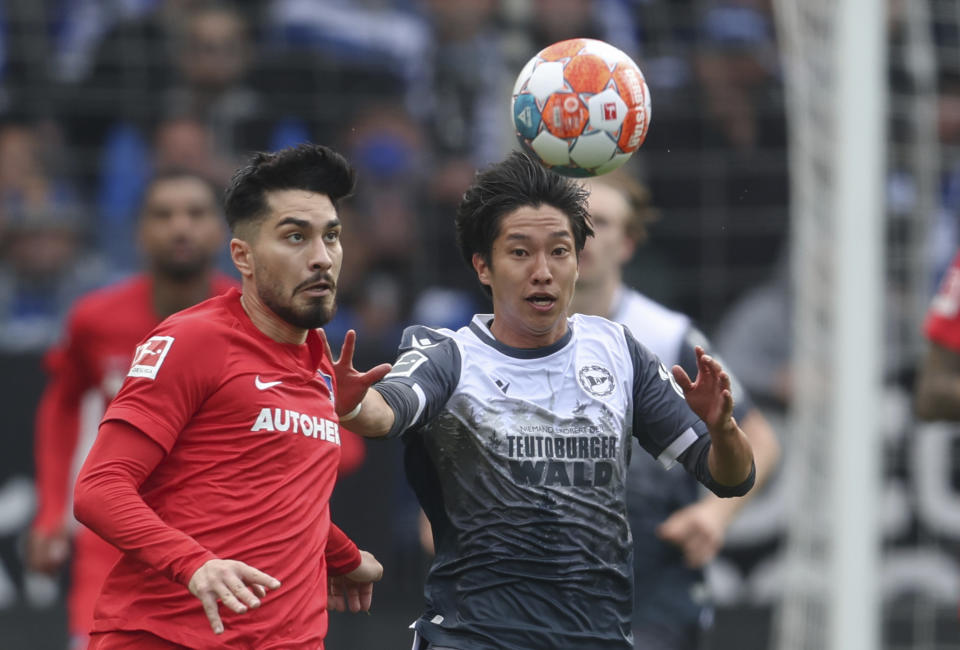 Masaya Okugawa del Arminia Bielefeld y Suat Serdar del Hertha Berlin pelean por el balón en el encuentro de la Bundesliga el sábado 30 de abril del 2022. (Friso Gentsch/dpa via AP)