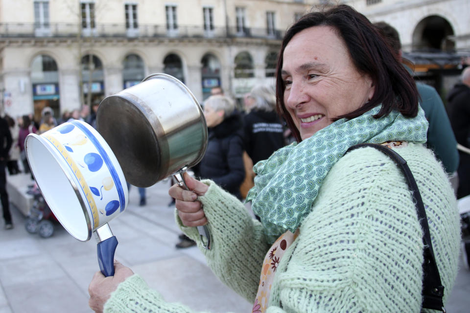A woman bangs pots and pans while French President Emmanuel Macron seeks to diffuse tensions in a televised address to the nation, Monday, April 17, 2023 in Bayonne, southwestern France. French President Emmanuel Macron, who just enacted protest-igniting pension changes, is expected to provide details about his domestic policies in the coming months. (AP Photo/Bob Edme)