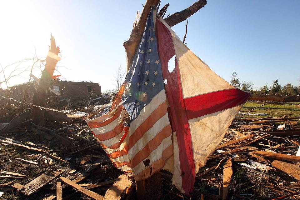 Brandon Cook attached an Alabama flag and American flag to what's left of a tree near Lisa Stacy's mother's home in the Holt community Friday, April 29, 2011. A deadly tornado ripped through Tuscaloosa Wednesday, April 27, 2011 leaving a wide trail of devastation. (Michelle Lepianka Carter / Tuscaloosa News)