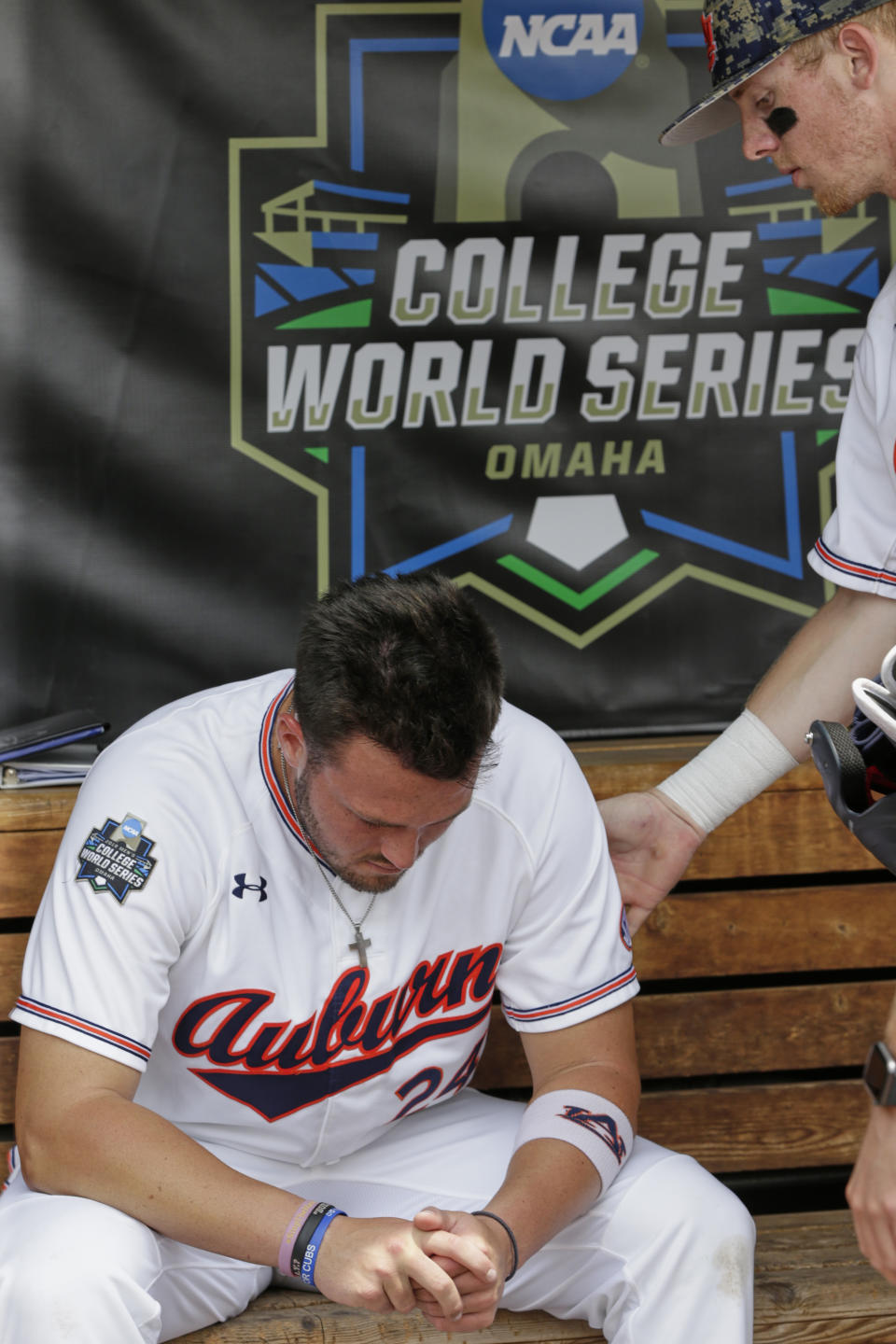 Auburn's Conor Davis (24) is comforted by a teammate in the dugout, following their 5-3 loss to Louisville, in an NCAA College World Series elimination baseball game in Omaha, Neb., Wednesday, June 19, 2019. (AP Photo/Nati Harnik)