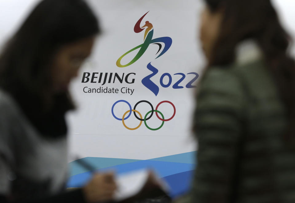 In this Nov. 4, 2014, file photo, journalists chat near the Beijing's bid for the 2022 Winter Olympics logo after attending a media briefing at the Beijing Olympics Headquarters in Beijing, China. A coalition of human-rights groups has met with the International Olympic Committee over calls to pull the 2022 Winter Olympics out of Beijing. (AP Photo/Andy Wong, File)