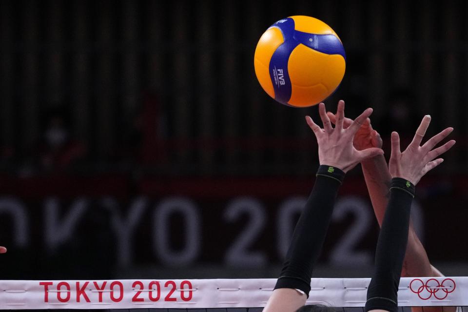 The hands of USA middle blocker Jordan Thompson and China setter Di Yao reach for an official FIVB Mikasa volleyball in a women's Pool B match during the Tokyo 2020 Olympic Summer Games at Ariake Arena on July 27, 2021.