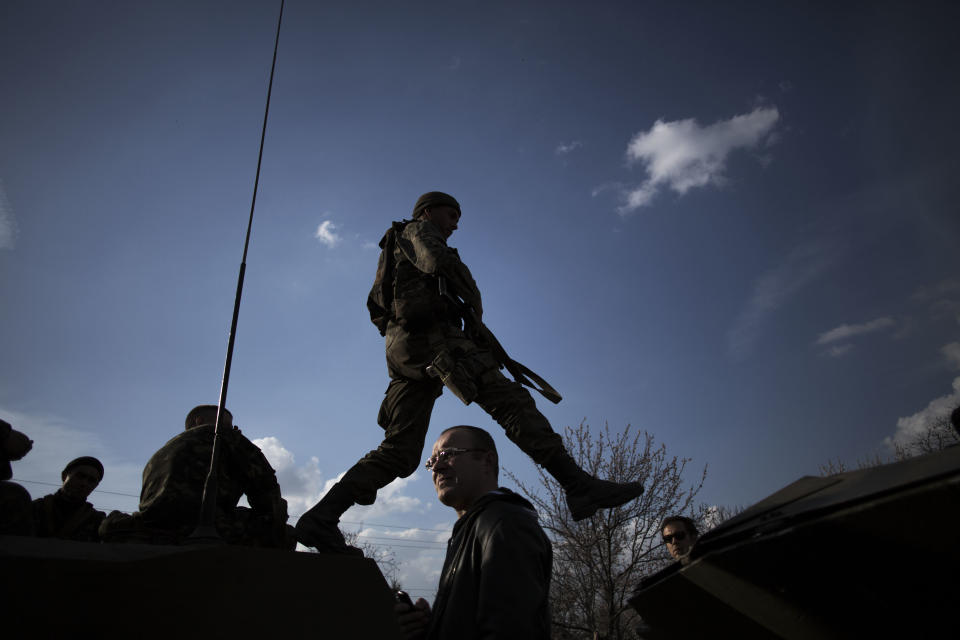 A soldier from the Ukrainian Army jumps on top of an armored vehicle, as they are blocked by people on their way to the town of Kramatorsk on Wednesday, April 16, 2014. Pro-Russian insurgents commandeered six Ukrainian armored vehicles along with their crews and hoisted Russian flags over them Wednesday, dampening the central government's hopes of re-establishing control over restive eastern Ukraine. (AP Photo/Manu Brabo)