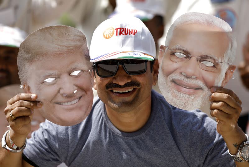 A man holds masks depicting U.S. President Donald Trump and Indian Prime Minister Narendra Modi during the "Namaste Trump" event attended by Trump and Modi at Sardar Patel Gujarat Stadium, in Ahmedabad