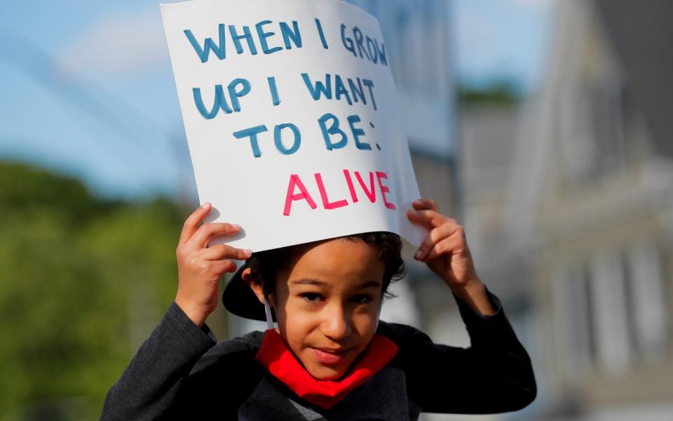 Six year-old Adam Neves holds a sign during a rally in Boston, Massachusetts - Reuters