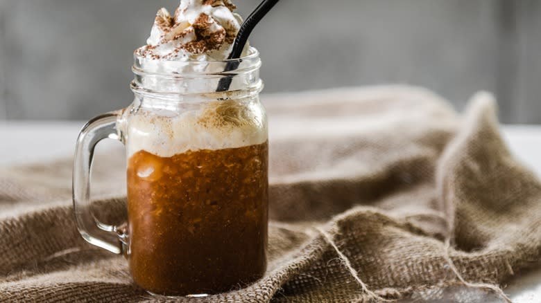 A chocolate iced coffee with whipped cream in a glass jar