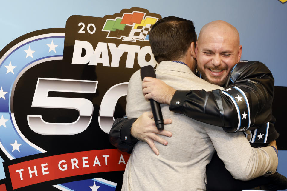 Entertainer Pitbull, right, hugs Daytona International Speedway president Frank Kelleher during a news conference after the NASCAR Daytona 500 auto race was postponed Sunday, Feb. 18, 2024, at Daytona International Speedway in Daytona Beach, Fla. (AP Photo/Terry Renna)