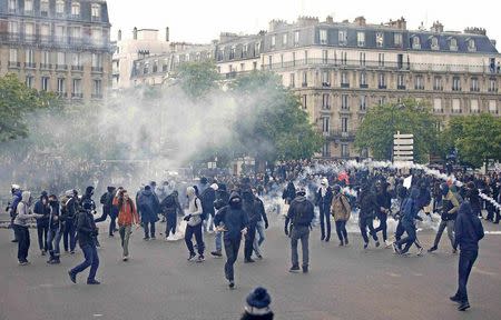 Masked youths run among tear gas during a demonstration against the French labour law proposal in Paris, France, as part of a nationwide labor reform protests and strikes, April 28, 2016. REUTERS/Charles Platiau