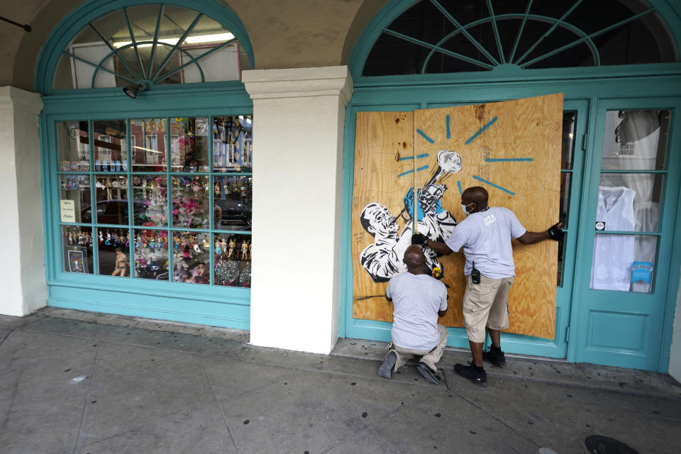 Workers board up shops in the French Quarter of New Orleans, Sunday, Aug. 23, 2020, in advance of Hurricane Marco, expected to make landfall on the Southern Louisiana coast. (AP Photo/Gerald Herbert)