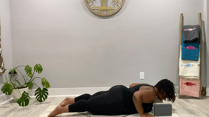 Woman lying on her belly with blocks beneath her shoulders during her 15-minute yoga practice