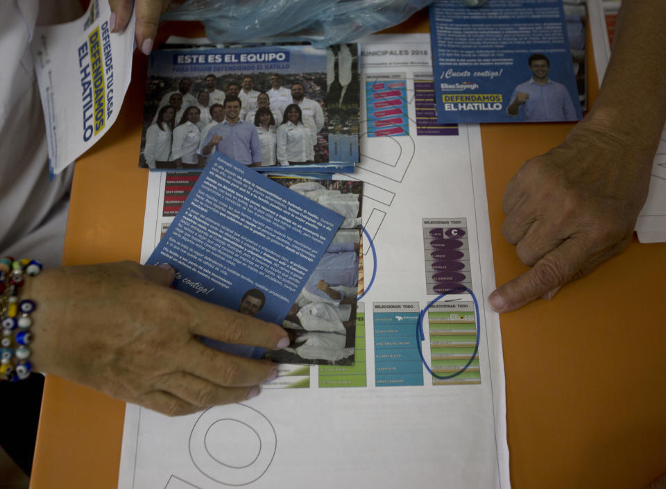 In this Dec. 5, 2018 photo, people are familiarized with the ballot for local elections during a campaign event by Fernando Melena, who is running to retain his council seat in the eastern district of El Hatillo, just outside Caracas, Venezuela. The elections have been overshadowed by the brutal economic crisis overwhelming the South American country, driving masses abroad in search of a better life. (AP Photo/Fernando Llano)